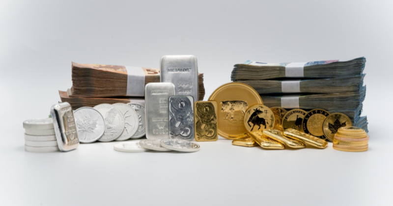 Gražiai surikiuota banknotų, auksinių ir sidabrinių monetų, luitų krūva